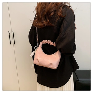 Détail du sac nuage plissé rose avec bandoulière en métal porté par un modèle