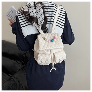 Close-up of a white quilted mini backpack featuring candy-colored bead decorations