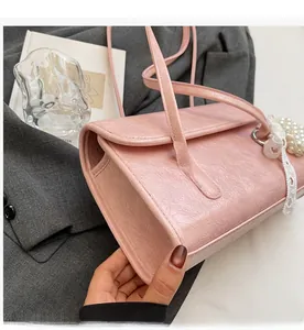 Detail of pink pleated faux leather tote bag with lace and pearl pendant on grey blazer