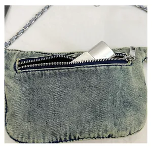 Close-up of light blue denim bag back pocket with metal zipper and chain strap