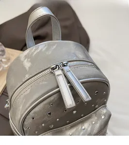 Detail of silver metallic quilted backpack with rhinestone studs and dual metal zippers