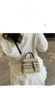 Détail du sac panier tressé avec rayures noires et bandoulière en cuir réglable