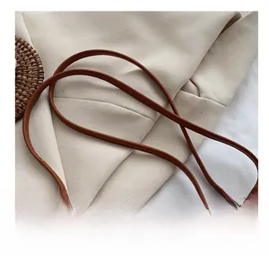 Detail shot of the brown leather shoulder strap on a handcrafted woven straw crossbody bag