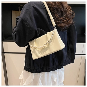 Détail du sac bandoulière plissé crème avec chaîne de perles et texture en cuir souple