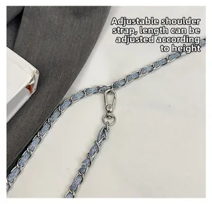 Detail view of adjustable denim woven metal chain shoulder strap with silver lobster clasp
