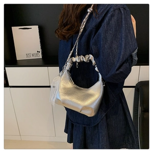 Détail du sac nuage argenté métallisé avec poignée plissée et breloque en dentelle blanche