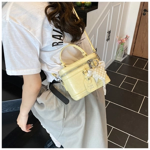Detail of light yellow patent leather mini bucket bag with pearl and lace charm decoration