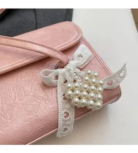 Detail of pink shoulder bag featuring pleated texture and heart pearl charm