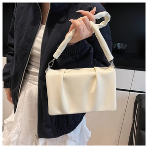Détail d'un sac à main en cuir plissé crème avec une poignée froncée élégante et perles
