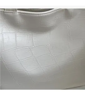 Close-up of premium white faux leather with embossed crocodile texture on a tote bag