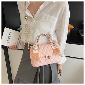 Close-up of pink quilted crossbody bag featuring a gold clasp and cute bear print ribbon