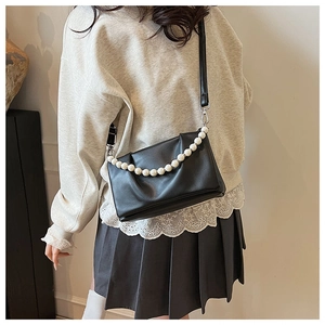 Détail du petit sac bandoulière noir avec chaîne de perles et bandoulière réglable