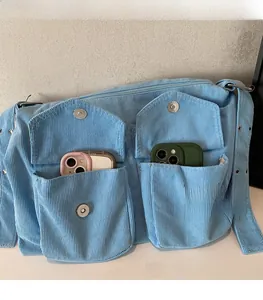 Détail du sac cabas en velours côtelé bleu clair avec doubles poches avant et boucles