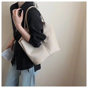 Detail of minimalist cream leather bucket bag showing soft lychee grain texture and magnetic closure