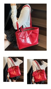 Detail view of large red tote bag featuring crocodile pattern texture and shoulder strap