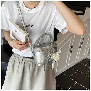 Detail of silver metallic bucket bag with pearl heart charm and round handle