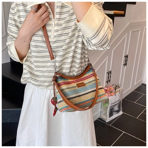 Détail du sac cabas en paille à rayures colorées avec bandoulière en cuir et fraise