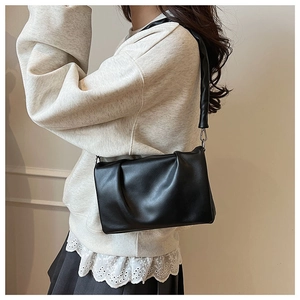 Détail du sac à bandoulière noir plissé en cuir mat avec large sangle de transport