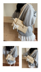 Detail of beige faux crocodile shoulder bag with lace bow and pearl pendant decoration