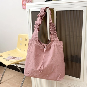 Close-up of light pink nylon tote bag with ruffle strap and silver stud details