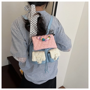 Detail of macaron quilted mini backpack featuring colorful pearl handle and drawstring