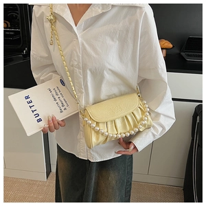 Détail du sac nuage plissé jaune crème avec chaîne en perles et bandoulière dorée