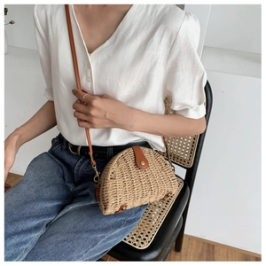 Detail of woven straw saddle bag with brown leather flap on a casual outfit