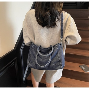 Détail du sac cabas en denim vintage avec surpiqûres blanches et bandoulière réglable