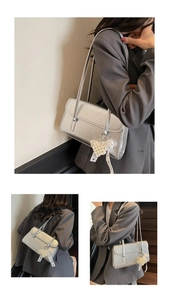Detail of silver metallic underarm bag featuring a pearl heart charm and lace bow decor