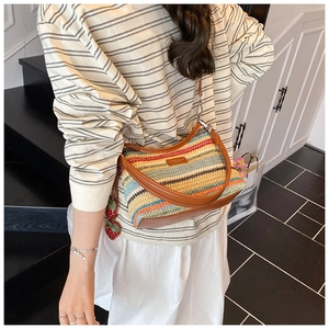 Détail du sac bandoulière tissé arc-en-ciel avec base en cuir brun et breloques fraises