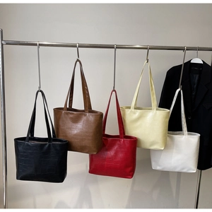 Detail of five croc-embossed tote bags in black, brown, red, yellow and white colors