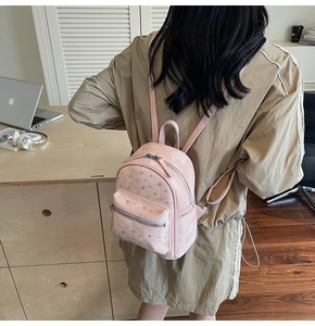 Pink mini backpack with silver rivets and quilted design shown on person in a cozy room