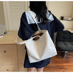 Detail of white crocodile texture tote bag with brown striped lining and handle straps