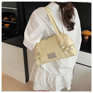 Detail of a creamy yellow Boston bag with silver hardware on a white lace dress