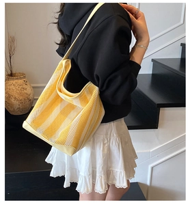 Detalle del bolso de malla a rayas amarillas y blancas con correas anchas para el verano