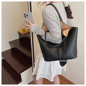 Detail of black pebbled leather bucket bag featuring a soft texture and heart charm