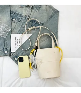 Detailed close-up of cream bucket bag with yellow drawstring handle and floral charm