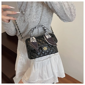 Detail of quilted chain box bag featuring a silk scarf wrapped handle and gold twist lock