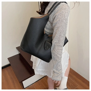 Close-up of black pebble leather bucket bag with decorative buckle and tan lining