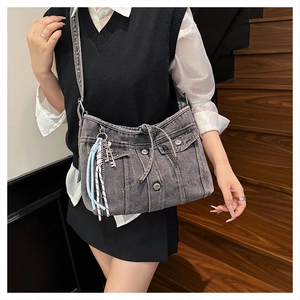 Détail du sac bandoulière en denim gris avec boucles vintage et pendentifs tissés décoratifs