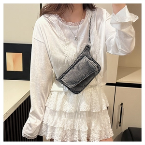 Detail of dark grey washed denim crossbody bag with metal chain strap and dual pockets