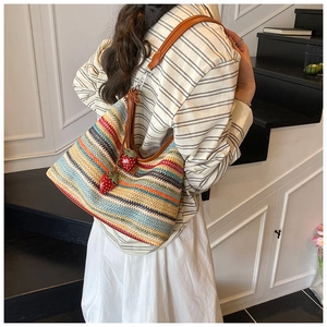 Détail du sac tissé arc-en-ciel avec breloques fraises et bandoulière en cuir marron