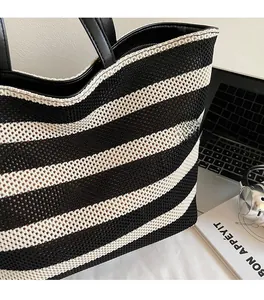Detail view of black and white woven tote bag with knit mesh texture and leather handles