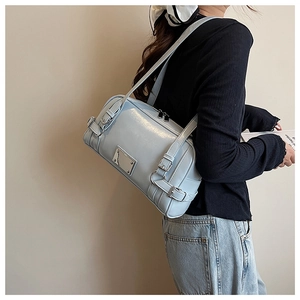 Model wearing a baby blue shiny leather Boston bag with silver metal plate detail