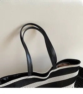 Detail of black and white woven tote bag with smooth synthetic leather shoulder straps