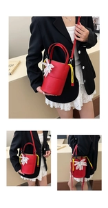 Detail of red bucket bag featuring 3D chiffon flower charm and yellow decorative rope accent