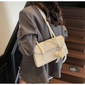 Detail of off-white cracked texture shoulder bag with pearl heart charm on a model