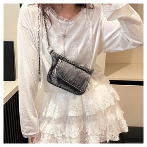 Close-up of vintage denim crossbody bag with flap pocket and silver chain strap details