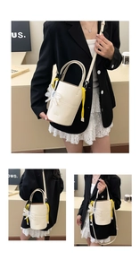 Detail of a creamy white bucket bag featuring floral charms and adjustable straps