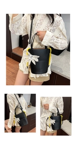Detail of black bucket bag featuring yellow drawstrings and a white flower charm accessory